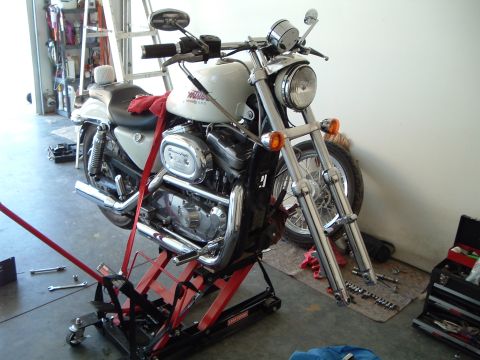 2000 Harley-Davidson Sportster - A white Harley-Davidson motorcycle is raised on a red lift in a garage, with tools laid out nearby.