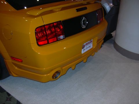 1996 Ford Crown Victoria - The rear of a yellow car is shown with a black panel between the taillights and a license plate frame.