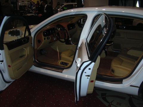 1996 Ford Crown Victoria - Interior view of a white luxury sedan with tan leather seats and wood trim, doors open.