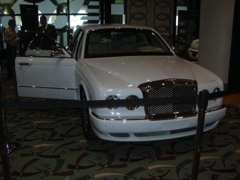 1996 Ford Crown Victoria - A white Bentley sedan is displayed indoors with its driver's door ajar.