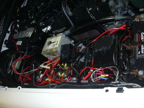 1996 Ford Crown Victoria - The image shows a close-up view of a vehicle's battery and a tangled network of electrical wiring and fuse boxes.