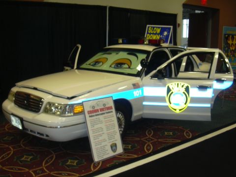 1996 Ford Crown Victoria - A police car, possibly a Ford Crown Victoria, is displayed with cartoon eyes on the windshield and its doors open.