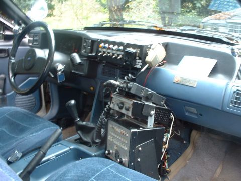 1987 Ford Mustang - The interior of a 1987 Ford Mustang shows extensive aftermarket radio equipment mounted on the dashboard and center console.