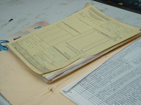 1987 Ford Mustang - A stack of documents, including forms and a ledger, sits on a surface.