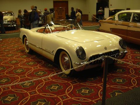 1996 Ford Crown Victoria - A white 1955 Chevrolet Corvette convertible is displayed indoors on a patterned carpet.