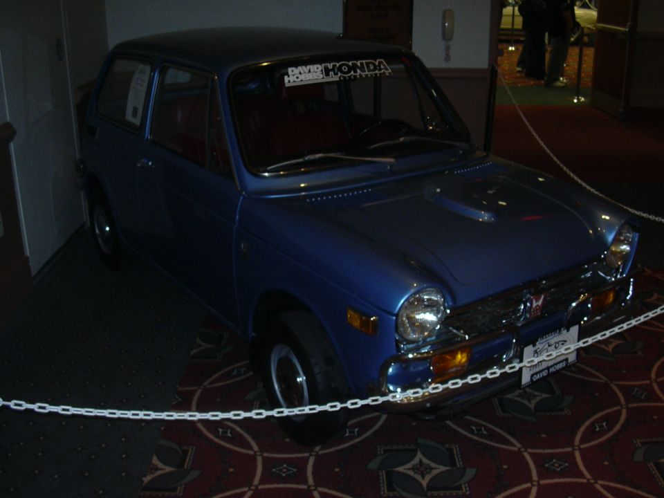 Blue 1970 Honda N600 parked indoors with a chain barrier in front