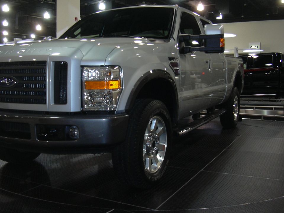 Silver pickup truck with chrome grille and headlights, seen from the front three-quarter angle
