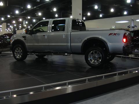 1996 Ford Crown Victoria - A silver Ford F-Series pickup truck is displayed on a rotating platform at an auto show.