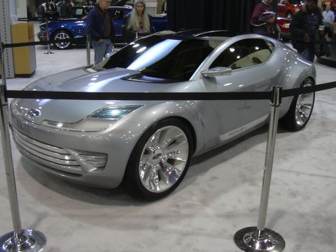 1996 Ford Crown Victoria - A futuristic silver concept car is displayed at an auto show.