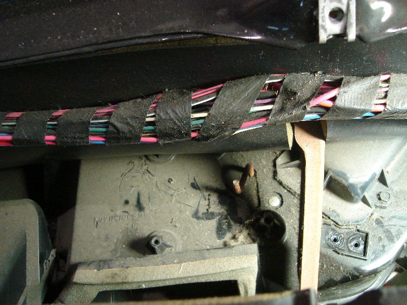 Close-up of a vehicle's interior wiring harness taped with black electrical tape