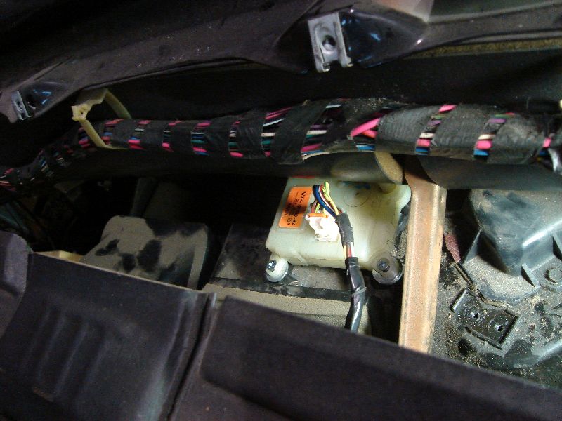 Vehicle interior with exposed wiring harness and a white fluid reservoir with an orange label