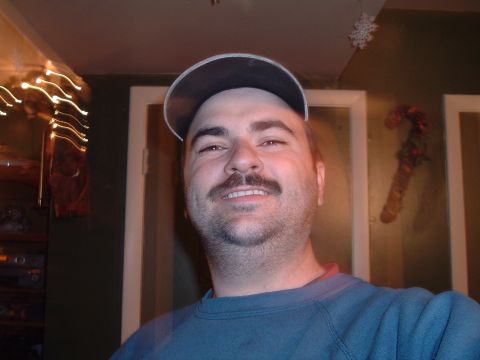 1986 Ford Bronco - A man with a mustache and a baseball cap is pictured indoors.