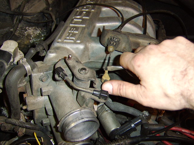 the tranny cable is removed by pulling towards yourself and lifting up. 
At the bracket towards the rear, use a pair of pliers to squeese the retaining clips together, thus allowing you to push the cable through.