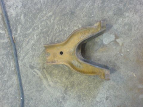 1967 Ford Bronco - A single automotive part, likely from a vehicle's suspension, lies on a concrete surface.