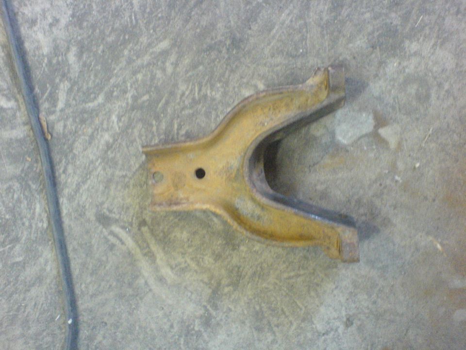 yellowish metal automotive part with a U-shaped opening and a hole
