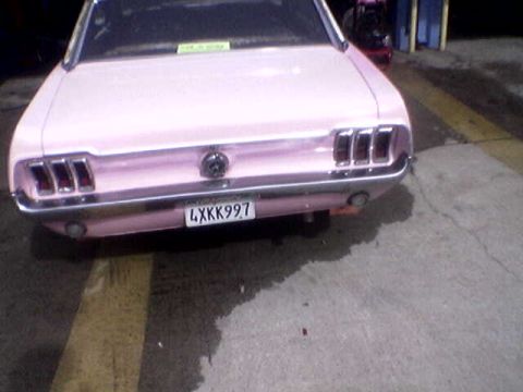 1988 Ford Bronco - Rear view of a pink 1967 Ford Mustang, showing its distinctive taillights and chrome bumper.