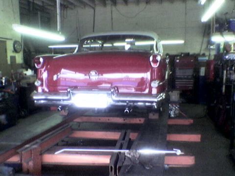 1988 Ford Bronco - Rear view of a classic red and white car on a lift in a garage.