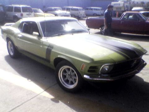 1988 Ford Bronco - A classic green Mustang is parked on a lot with other vehicles visible in the background.