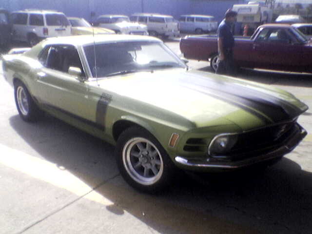 Light green 1970 Ford Mustang fastback with black Boss-style stripes parked in a lot