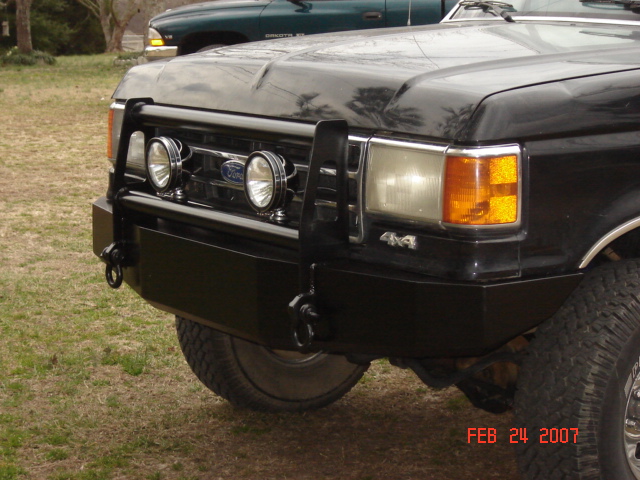 Front of black Ford Bronco with custom steel bumper, brush guard, and dual round driving lights