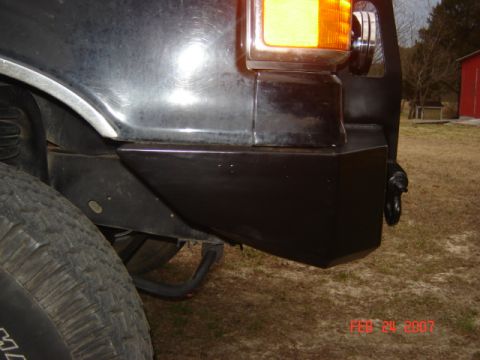 1990 Ford Bronco - Rear bumper and tire detail, with a red barn visible in the distance.