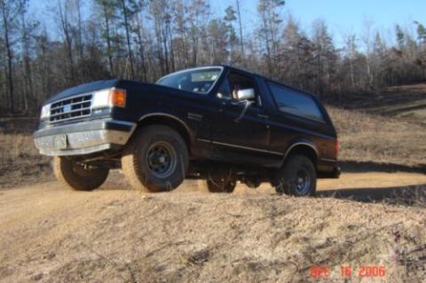 1990 Ford Bronco - This 1990 Ford Bronco navigates an off-road trail with a clear blue sky overhead.