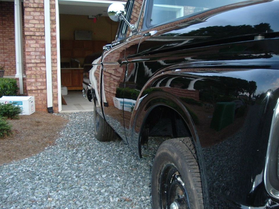 Side view of a black 1966 Ford F-100 pickup truck parked in a driveway