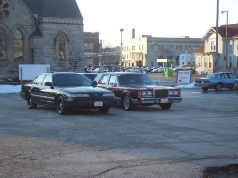1992 Ford Crown Victoria - A black 1992 Ford Crown Victoria is parked next to a maroon sedan in a lot.