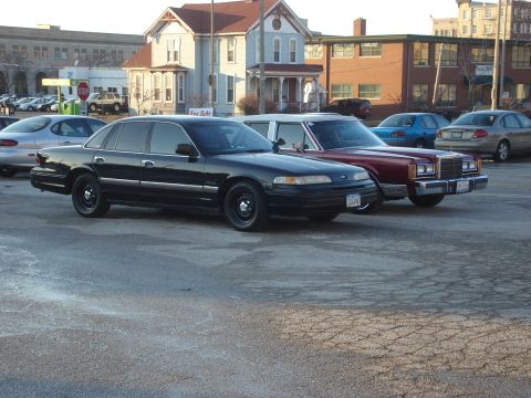 1992 Ford Crown Victoria - A black 1992 Ford Crown Victoria is parked in a lot next to other vehicles.