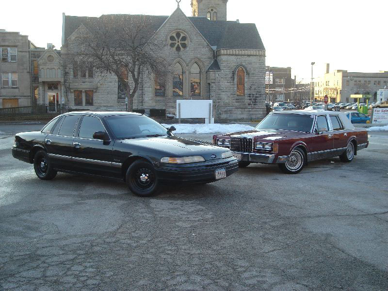 black sedan and maroon sedan parked next to each other in front of a building
