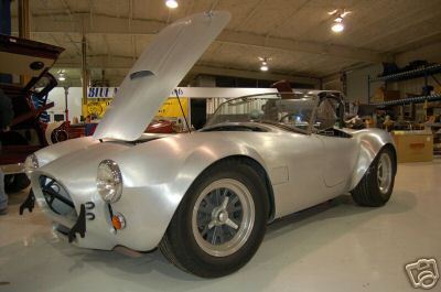 1965 Shelby Cobra - This unpainted aluminum roadster, possibly a kit car, is shown with its hood open.
