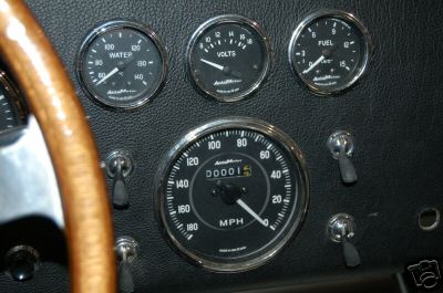 1965 Shelby Cobra - Close-up of a car's dashboard, showing various gauges and a portion of the steering wheel.