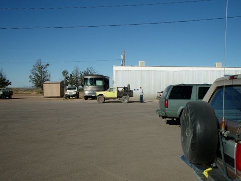 1996 Ford Bronco - A variety of vehicles are parked in an outdoor lot under a clear blue sky.