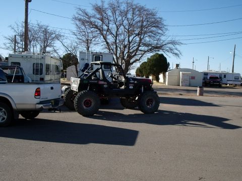 1996 Ford Bronco - A heavily modified off-road buggy with large tires is parked next to a pickup truck and RVs.