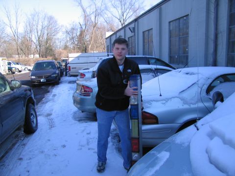 1991 Ford Crown Victoria LTD - A man stands in a snowy lot, holding a car's tail light assembly.
