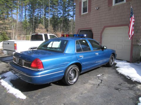 1991 Ford Crown Victoria LTD - Blue police car with light bar parked in driveway next to a white pickup truck.