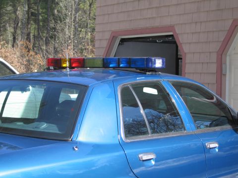 1991 Ford Crown Victoria LTD - A blue police car with a light bar is parked in front of a garage. The vehicle appears to be a 1991 Ford Crown Victoria LTD.