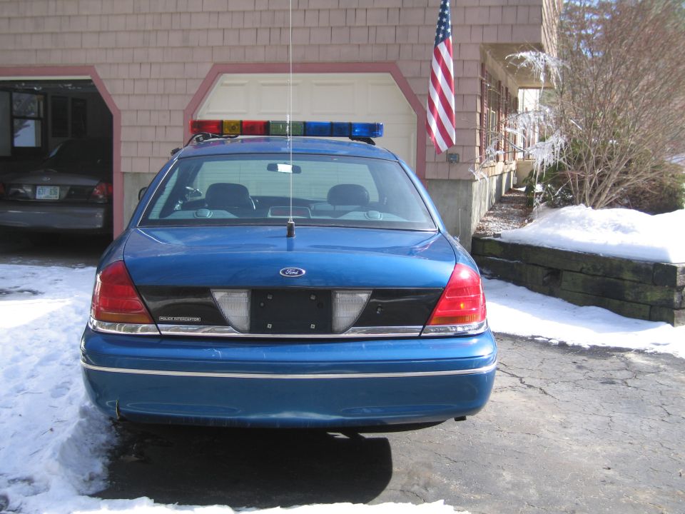 Rear view of blue police car with light bar and American flag