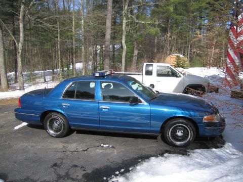 1991 Ford LTD Crown Victoria - A blue police sedan is parked next to a white pickup truck in a snowy area.