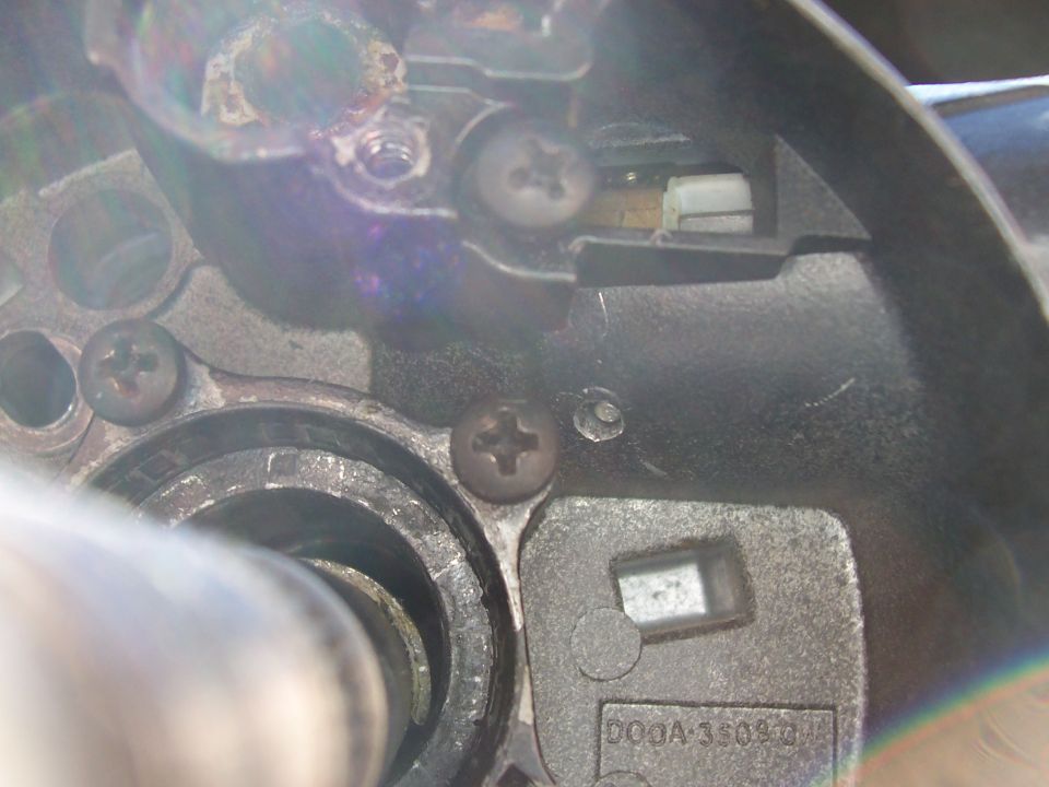 Close-up of steering column ignition lock mechanism with screws and housing