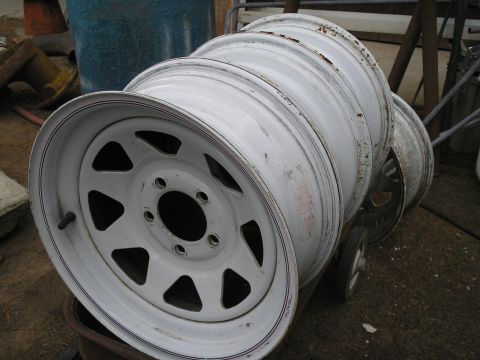 1990 Ford Bronco - A stack of white rims, likely for a truck or SUV, are shown with visible wear and tear.