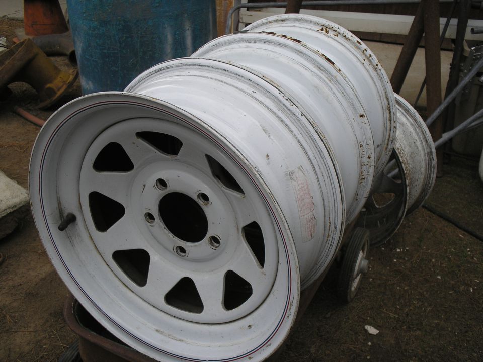 Stack of white rims with five spokes, some with visible wear