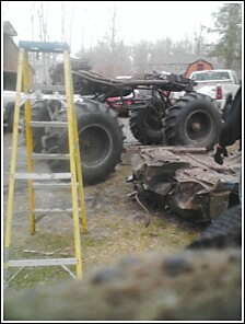 2004 Jeep Wrangler - A vehicle with oversized tires is visible, alongside a yellow ladder and other debris.