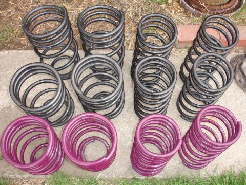 1993 Ford Taurus - Collection of suspension coil springs, some black and some purple, arranged outdoors.