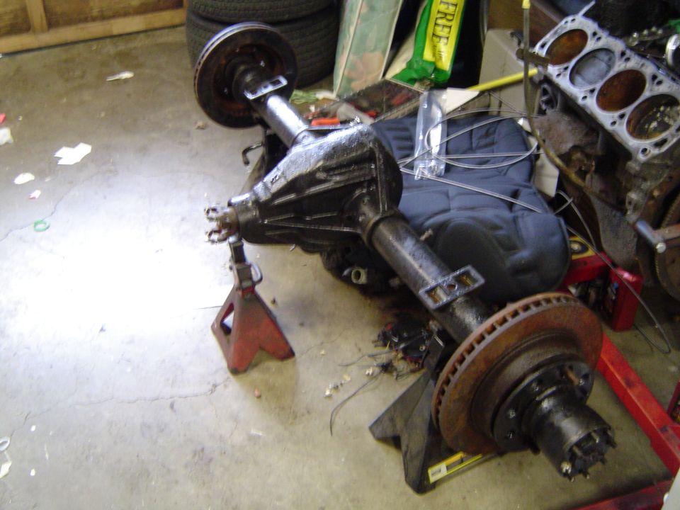 Removed solid rear axle with brake drums on a garage floor