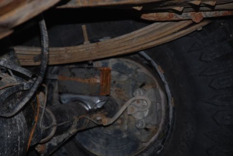 1996 Ford Bronco - Close-up view of a vehicle's rear axle and suspension system, revealing rusty components and a brake drum.