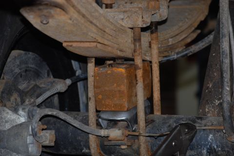1996 Ford Bronco - Close-up view of a vehicle's rear suspension, showing leaf springs, a block lift kit, and U-bolts.