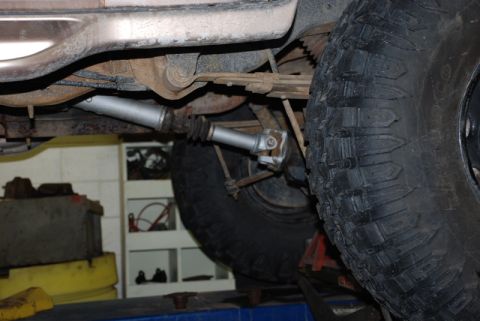 1996 Ford Bronco - Close-up of a vehicle's driveshaft and suspension components, including a tire and leaf spring.
