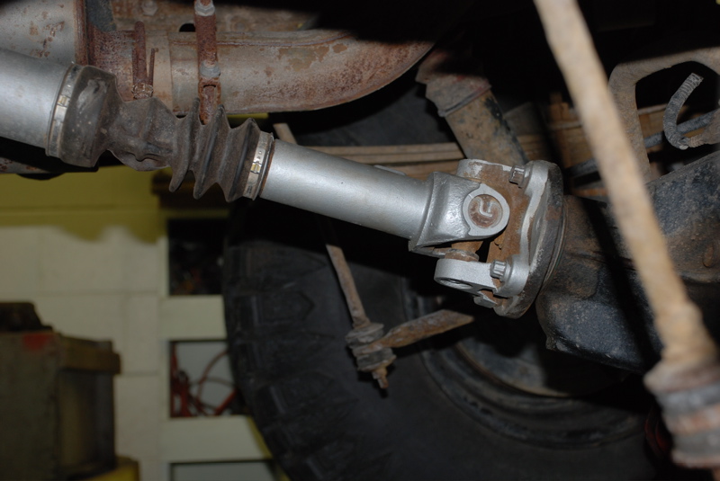 Close-up of a vehicle's driveshaft and U-joint, showing rust and wear