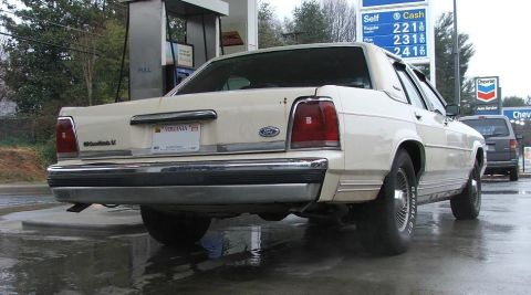 1991 Ford Crown Victoria LTD - Rear view of a 1991 Ford Crown Victoria LTD at a gas station with a minivan in the background.